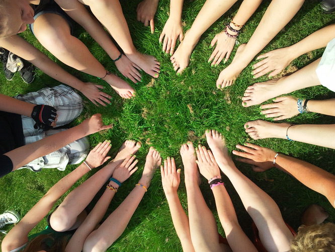 A circle of hands on a lawn (Photo: Henning Westerkamp, CC0 1.0)